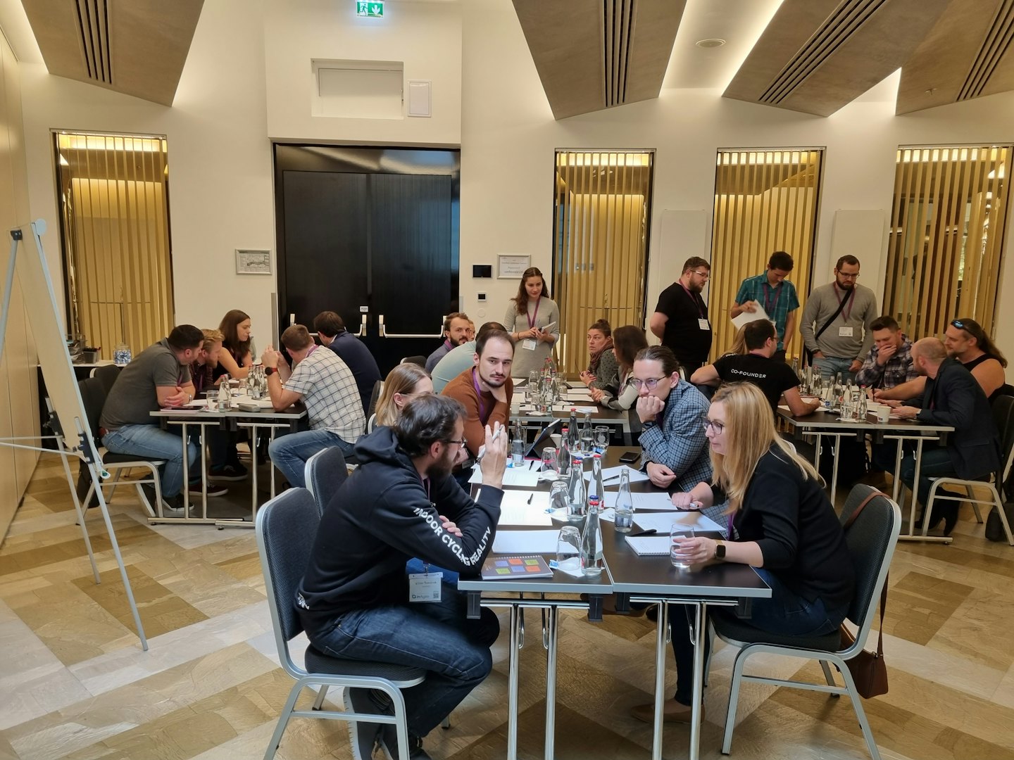 Adulti che partecipano a un workshop aziendale attorno a tavoli.