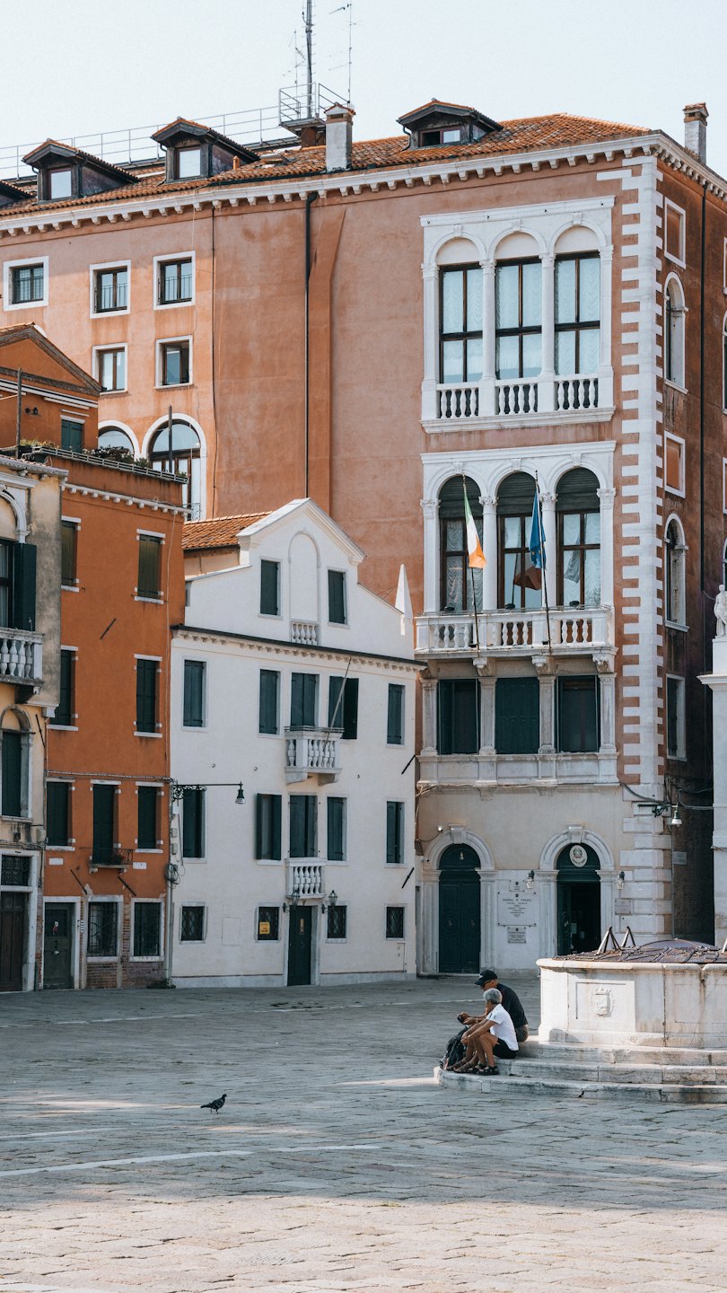 Due persone siedono sui gradini di una fontana di pietra.