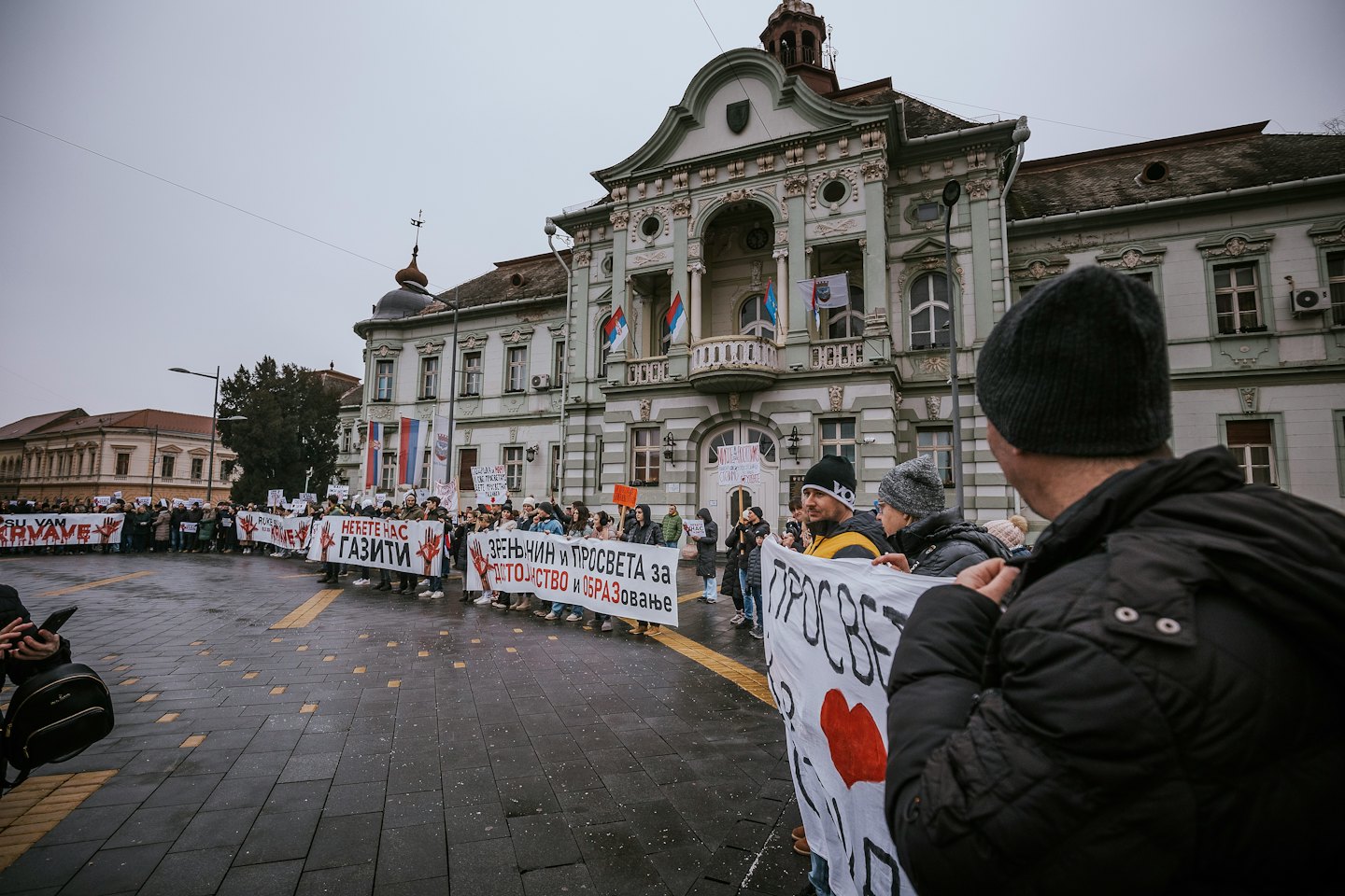 Manifestanti con cartelli e striscioni in una piazza cittadina.